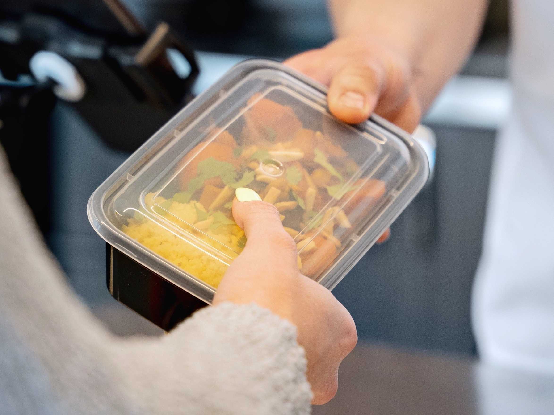 Visitor purchasing meal in a take-out container from a café.